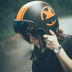 Ragazza con casco moto nero e arancione, occhiali riflettenti. Guida sicura: ecco come scegliere casco moto.