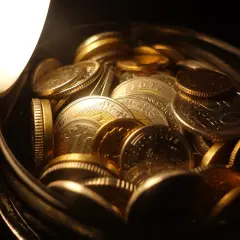 Złote monety w słoiku, symbolizujące pierwsza linia dziedziczenia. Blask światła podkreśla ich wartość i bogactwo.