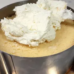 Nakładanie puszystej masy z mascarpone na biszkopt w tortownicy.