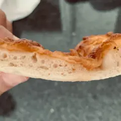 Rebanada de pizza con burbujas perfectas en la masa, dorada y crujiente.