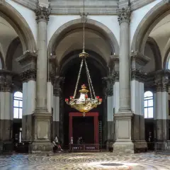 Intérieur de la basilique Santa Maria della Salute, avec son lustre imposant, ses colonnes majestueuses et son sol orné.