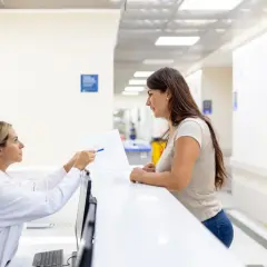 Rejestratorka medyczna pokazuje pacjentce dokumenty. Idealny przykład pracy po kursie rejestratorka medyczna.