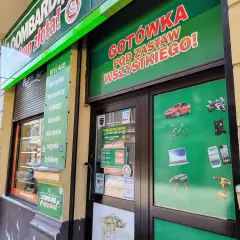 Szyld lombardu z napisem "GOTÓWKA POD ZASTAW WSZYSTKIEGO!" i grafikami przedmiotów.