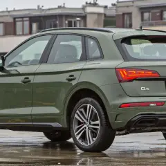Zielony Audi Q5 na mokrym parkingu. Poznaj jego **audi q5 wymiary** i możliwości.
