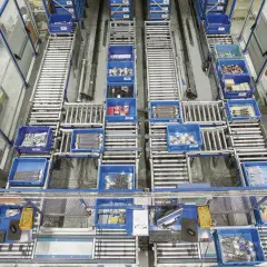 Ein Lager mit Rollenbahnen und blauen Behältern, die Werkzeuge und Materialien enthalten. Dies zeigt die Effizienz und Organisation, die durch Kanban-Vorteile erreicht werden.