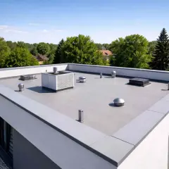 Nowoczesna attyka z płaskim dachem, wentylacją i klimatyzacją, otoczona zielenią.