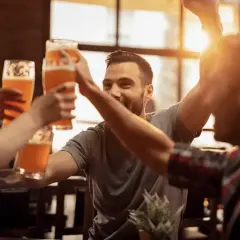 Uśmiechnięci ludzie wznoszą toasty piwem w jednym z najlepszych pubów w Warszawie.