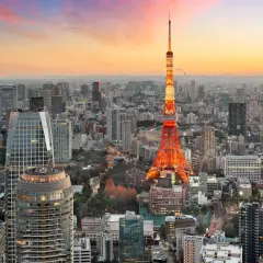 Wieżowiec Tokyo Tower oświetlony na czerwono na tle rozległego, największego miasta na świecie, Tokio, podczas zachodu słońca.