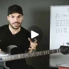 Hombre con bajo explica qué es el ska con un diagrama musical en una pizarra.