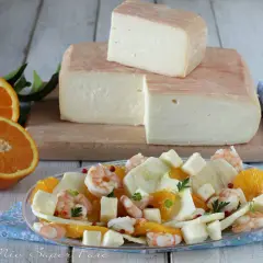 Un blocco di formaggio taleggio stagionato, pronto per essere gustato con un'insalata fresca di arance, finocchi e gamberetti.