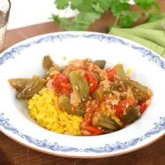En tallrik med okra och tomater i en kryddig sås, serverad med gul ris. Ett läckert bamya recept för en smakrik måltid.