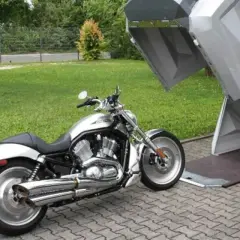 Srebrny motocykl czeka na schowanie w nowoczesnym, otwartym stojaku na skuter.