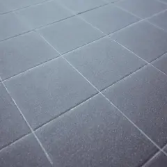 Dettaglio di piastrelle grigie con fughe pavimento pulite e uniformi, che creano un motivo geometrico ordinato.