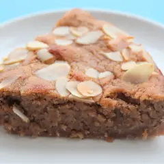 Tranche de gâteau à la crème de marron, garnie d'amandes effilées, sur une assiette blanche.
