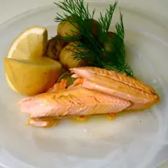 Hel regnbåge i ugn, serverad med småpotatis, citron och dill. En vacker och smakrik rätt.