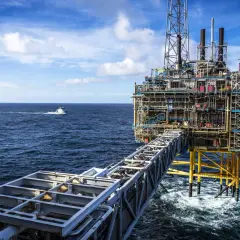 Ölplattform im Meer, die den Reichtum des norwegischen Staatsfonds repräsentiert. Ein Versorgungsschiff fährt vorbei.