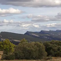 Paisaje montañoso con formaciones rocosas afiladas, típico de fotos de ojo Guareña. Nubes blancas y cielo azul.