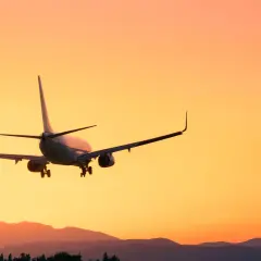 Flugzeug im Landeanflug bei Sonnenuntergang. Man fragt sich, wie viel eher am Flughafen sein, um diesen Anblick zu genießen.