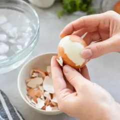 Mains épluchant un œuf dur. Attention, un œuf congeler danger, car il peut exploser à la cuisson.