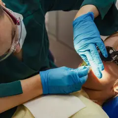 Dentystka wykonuje lakowanie zębów u dziecka. Sprawdź, jaka jest lakowanie zębów cena i zadbaj o uśmiech swojej pociechy.
