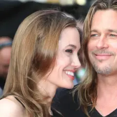 Angelina Jolie i jej mąż Brad Pitt uśmiechają się do siebie na czerwonym dywanie.