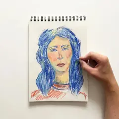 Portret kobiety z niebieskimi włosami, tworzony pastelami. Ręka dodaje ostatnie pociągnięcia, tworząc efekt dragana.