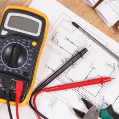 Narzędzia elektryka i schemat instalacji elektrycznej. Multimetr, śrubokręt, kombinerki i przewody gotowe do wykonania oświadczenia elektryka o wykonaniu instalacji elektrycznej.