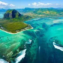 Widok z lotu ptaka na Le Morne Brabant, Mauritius, gdzie leży ta wyspa. Turkusowa woda, rafy koralowe i góra tworzą iluzję podwodnego wodospadu.
