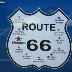 Tablica z napisem "ROUTE 66" i odległościami do miast, np. Chicago, Los Angeles. To symbol legendarnej drogi 66 w USA.