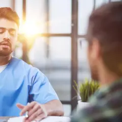 Lekarz w niebieskim kitlu rozmawia z pacjentem. Czy do psychiatry potrzebne jest skierowanie? Zapytaj lekarza.