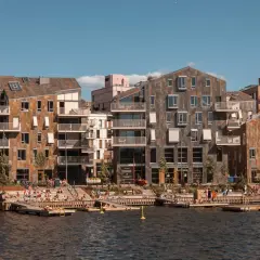 Moderne Architektur am Wasser in Oslo. Menschen entspannen sich auf Holzdecks, ein perfekter Ort für Oslo Sightseeing.