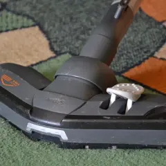 Cabezal de aspiradora sobre alfombra. Parece que la aspiradora huele mal, necesita una limpieza profunda.