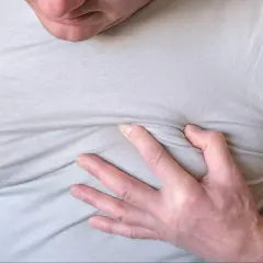 Mężczyzna trzyma się za klatkę piersiową, odczuwając niepokojące pieczenie.