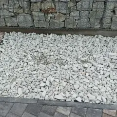Jasny grys dolomitowy tworzy estetyczną ścieżkę obok gabionów i innych kruszyw.