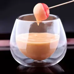 Une tomate cerise trempée dans une sauce cocktail onctueuse, servie dans un verre élégant.