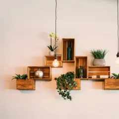 Scaffali in legno a forma di cassa, decorati con piante e oggetti, mostrano come attaccare una mensola al muro con stile.