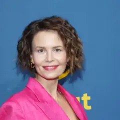 Magdalena Kumorek w różowej marynarce, uśmiechnięta na tle niebieskiego baneru.