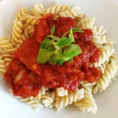 Fusilli con la mejor salsa de tomate italiana, cubierta con una hoja verde fresca.