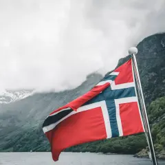 Norwegia: malownicze fiordy i wysokie norwegia zarobki netto. Flaga powiewa na maszcie, zapraszając do odkrywania piękna i możliwości.