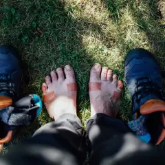 Fötter med plåster och vandringsskor på gräs. Kanske dags för nya vandringsstrumpor sommar?