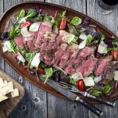 Tagliata succulenta in friggitrice ad aria, servita con insalata mista, scaglie di parmigiano e pomodorini.