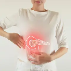 Kobieta z bólem brzucha, gdzie widoczny jest zarys trzustki. Czy rak trzustki jest dziedziczny?
