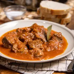 Sabrosa carne guisada con tomate, tiernos trozos de carne en una rica salsa, servida en un plato blanco.