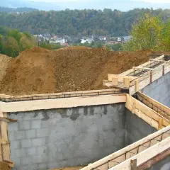 Fundamenty domu w budowie, zbrojenie i szalunki gotowe do zalania betonem. Pozwolenie na budowę wydane, marzenia o domu nabierają kształtów.