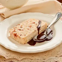 Delizioso semifreddo alla mandorla con salsa al cioccolato su un piatto bianco, pronto per essere gustato.