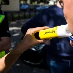 Policjant bada pracownika alkomatem.