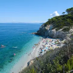 Spiaggia affollata vicino a Campiglia Marittima, con gente che prende il sole e nuota nelle acque cristalline.