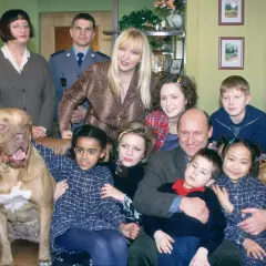 Wesoła rodzina zastępcza z psem i policjantem.