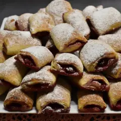 Stos ciasteczek z wiśniami, posypanych cukrem pudrem, wygląda apetycznie.