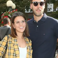 Monika Sawka z mężem, uśmiechnięci, w okularach, na tle drzew i ludzi.